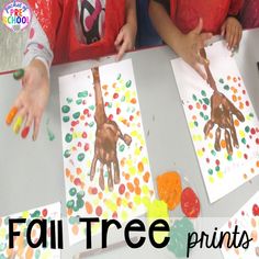 two children sitting at a table making handprints on paper with the words fall tree prints