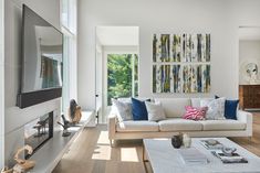 a living room filled with furniture and a flat screen tv mounted on a wall above a fire place