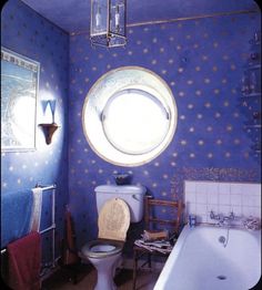 a bathroom with a toilet, sink and bathtub next to a round window in the wall