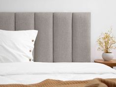 the headboard of a bed with white sheets and pillows