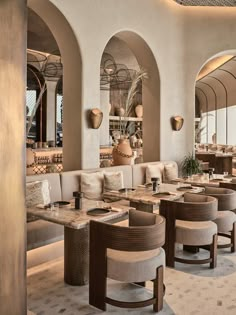 a restaurant with tables and chairs in front of an arched wall that has arches on it