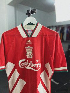 an old liverpool shirt hanging on a hanger in a room with other items behind it