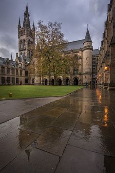 a large building with a clock tower on it's side and grass in the foreground