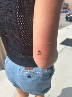 a person with a small tattoo on their left arm and the other hand behind her back