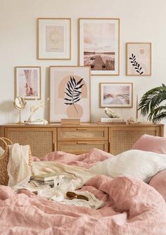 a bed with pink sheets and pictures on the wall above it, along with a wicker dresser