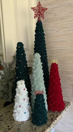 three crocheted christmas trees sitting on top of a counter next to each other