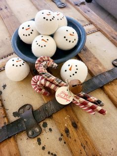 some snowmen are sitting in a bowl on a table next to an old pair of scissors