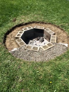 an open fire pit in the middle of some grass