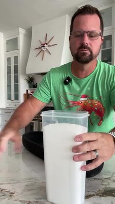 a man sitting at a kitchen counter with a glass of milk in front of him