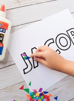 a child's hand is holding a crayon stick over a paper cutout with the word scotts on it