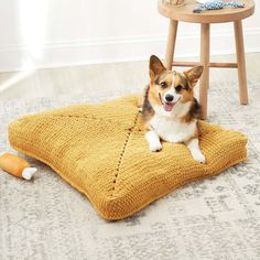 a small dog laying on top of a yellow blanket next to a wooden table and chair