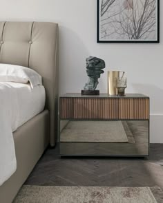 a bed sitting next to a nightstand on top of a wooden floor