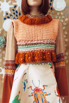 a close up of a mannequin's torso wearing an orange sweater and skirt