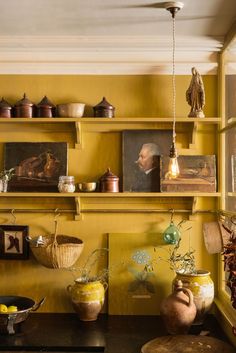 a kitchen with yellow walls and shelves filled with pots, pans and other items