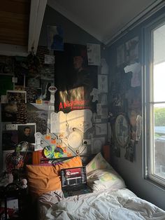 a messy bedroom with posters and pictures on the wall above the bed in front of a window