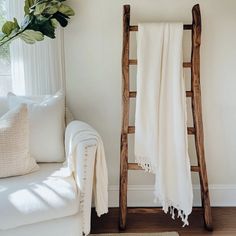 a white couch sitting next to a wooden ladder with a blanket on top of it