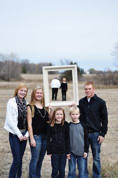 a family posing for a photo with an empty picture frame in front of their heads