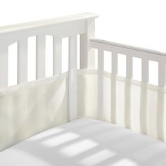 an empty crib with white sheets on it