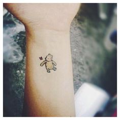 a small teddy bear tattoo on the wrist