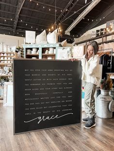 a woman standing next to a large sign in a room with wooden floors and ceilings