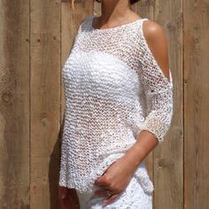 a woman standing in front of a wooden fence wearing a white top and short shorts