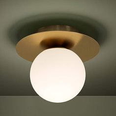 a round light fixture with a white ball on the top and a green wall in the background