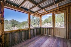 an empty room with wooden flooring and large windows overlooking the mountain range in the distance