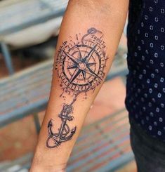 a man's arm with a compass and an anchor tattoo on the left forearm