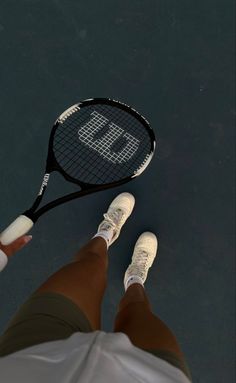 a person standing on a tennis court holding a racquet in their hand with the letter b on it