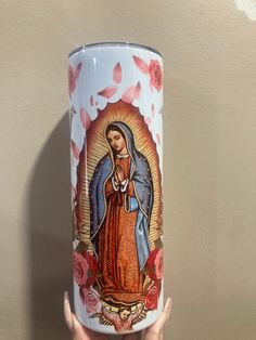 a hand holding a white coffee cup with an image of the virgin mary on it