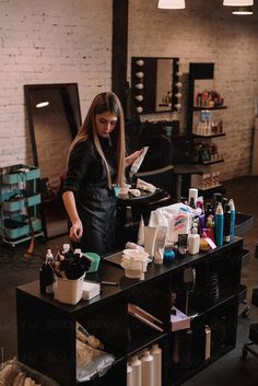 a woman standing in front of a table with lots of hair products on top of it