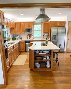 an open kitchen with wooden floors and stainless steel appliances in the center, along with hardwood flooring