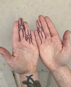 two hands with tattoos on their palms and one holding the other's hand up