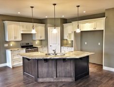 a large kitchen with an island in the middle and white cabinets on either side of it