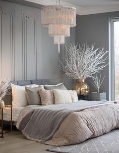 a large bed sitting in a bedroom next to a window with a chandelier hanging above it