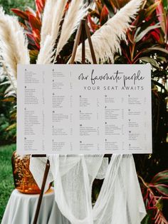 a seating chart for an outdoor wedding with flowers and greenery in the back ground