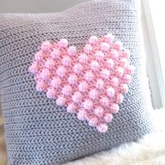 a crocheted pillow with a pink heart on it