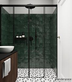 a black and white tiled bathroom with green tiles on the shower wall, sink and mirror