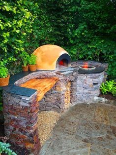 an outdoor stone oven surrounded by trees and plants