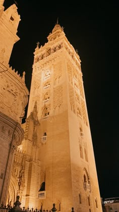 a tall building with a clock on the side of it's face at night