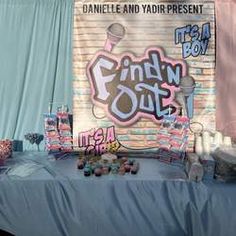 a blue table topped with lots of candy covered in pink and white frosting next to a brick wall