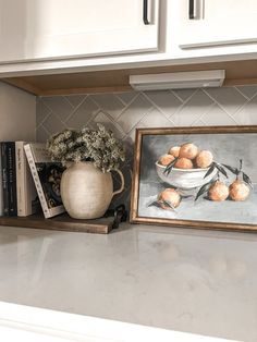 a white kitchen counter top with a painting and vase filled with flowers next to it