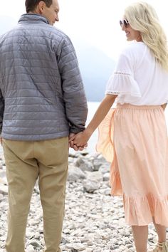 a man and woman holding hands while standing on rocks