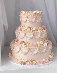 a three tiered wedding cake with pink frosting and pastel flowers on top