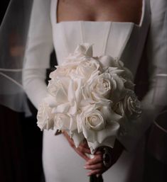 a bride holding a bouquet of white roses