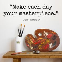 a wooden table topped with art supplies and a quote about making each day your masterpiece