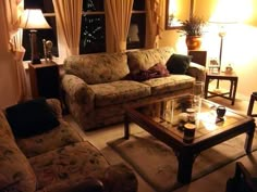 a living room with couches, tables and lamps on the windowsill in front of them