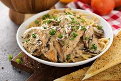 a white bowl filled with pasta covered in mushroom sauce and garnished with parsley