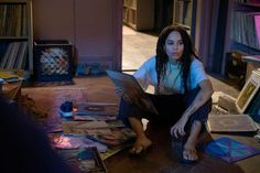 a woman sitting on the floor with a laptop computer in her hand and lots of cds around her