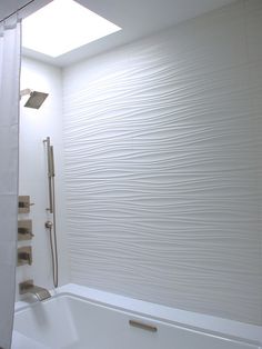 a white bath tub sitting next to a shower with a skylight in the background